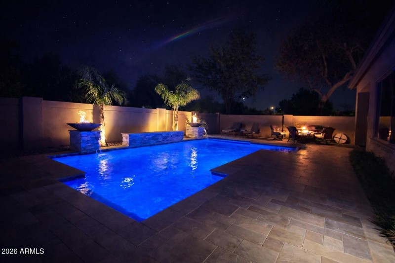 Nighttime backyard oasis with pool